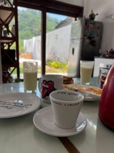 里約熱內盧的住宿－Casa Cristo Redentor c/piscina，桌子上放有盘子和杯子,上面放有饮料