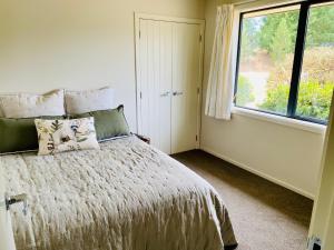 特威澤爾的住宿－Ben Ohau Villa，卧室配有带枕头的床铺和窗户。
