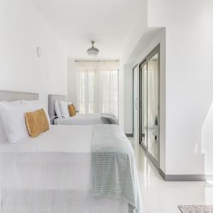 a white bedroom with two beds and a window at Oceanview lux Villa + Infinity pool, Chef & Butler in Kings Pen