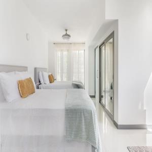 a white bedroom with two beds and a window at Oceanview lux Villa + Infinity pool, Chef & Butler in Kings Pen +14 photos