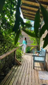 a woman is standing on a wooden deck at Pousada Vale da Magia in Praia do Rosa