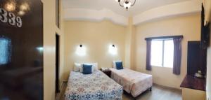 a bedroom with two beds and a window at Hotel Sevilla in Guatemala
