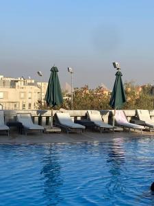 un grupo de sillas y sombrillas junto a una piscina en K Boutique Pyramids View West, en El Cairo