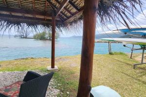 a beach with an umbrella and chairs and the ocean at Vaiana Home 2 - bord de lagon in Taputapuapea