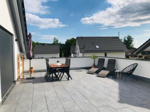 un patio avec une table et des chaises sur un toit dans l'établissement FERIENWOHNUNG SEEBRISE mit sonniger Dachterrasse, à Uhldingen-Mühlhofen