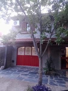 uma garagem vermelha com uma árvore em frente em Alojamiento por día Merlo San Luis em Merlo