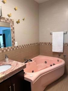 La salle de bains est pourvue d'une baignoire rose et d'un lavabo. dans l'établissement Quinta Eloísa, à Cuernavaca