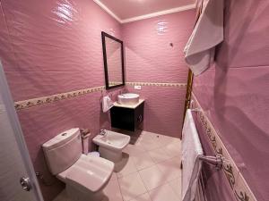 een roze badkamer met een toilet en een wastafel bij Elite Holiday Home - Luxury & Centric Flat in Tanger