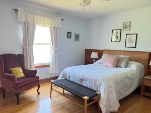 a bedroom with a bed and a chair and a window at COIS FARRAIGE BESIDE The SEA in North Rustico