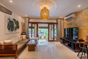 un salon avec un canapé et une télévision dans l'établissement Sama Sama Villa, à Nusa Dua