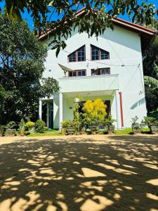 uma casa branca com árvores em frente em Haus Berlin em Negombo