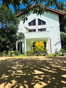 una casa bianca con degli alberi di fronte di Haus Berlin a Negombo