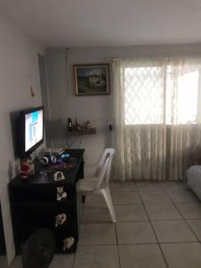 Habitación con escritorio, TV y silla. en 5 Minutos da Praia de Itapema en Itapema