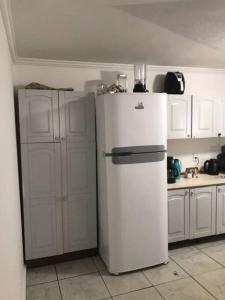 a white refrigerator in a kitchen with white cabinets at 5 Minutos da Praia de Itapema in Itapema
