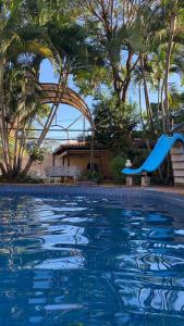 een blauwe glijbaan in een zwembad met palmbomen bij RESIDENCIA-UNIV in Ciudad del Este