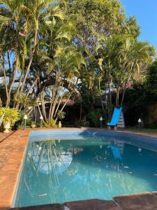 a swimming pool with a slide and palm trees at RESIDENCIA-UNIV in Ciudad del Este