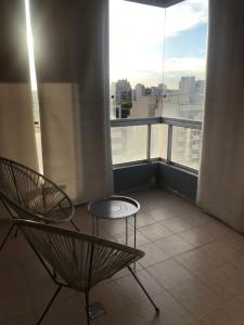 Un balcón con 2 sillas y una mesa frente a una ventana en Excelente departamento con ubicación ideal en Buenos Aires