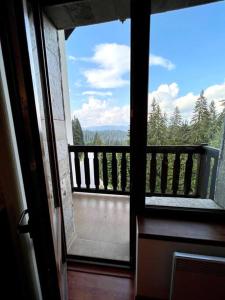 una puerta abierta a un balcón con vistas al bosque en 1-bedroom deluxe condo in Pamporovo, en Pamporovo