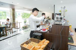 Ein Mann steht in einer Küche und bereitet Essen vor. in der Unterkunft New Century Hotel Cau Giay in Hanoi