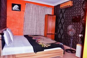Schlafzimmer mit einem Bett, einem Fenster und einem Ventilator in der Unterkunft Trending Place Hotel and Suites in Lagos
