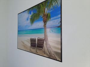 two chairs on the beach under a palm tree at Apartamento Peterle 101 IRIRI in Anchieta