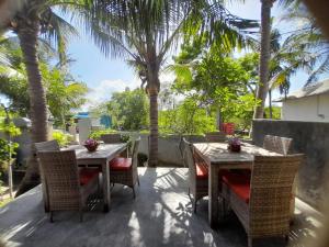 a patio with two tables and chairs and palm trees at Jiva Bungalow in Nusa Lembongan