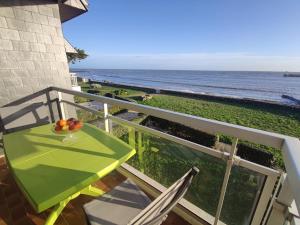 a green table and chairs on a balcony with the ocean at Appartement 3P avec Balcon et Parking - Sarzeau - FR-1-639-1 in Sarzeau