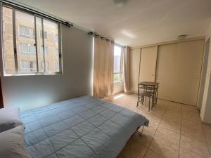 Un dormitorio con una cama y una mesa. en Apartamento completo amoblado Santiago cercano Movistar Arenas, en Santiago
