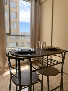 una mesa con dos sillas, platos y vasos. en Apartamento completo amoblado Santiago cercano Movistar Arenas, en Santiago