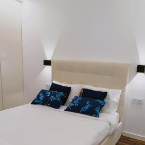 a white bed with two blue pillows on it at A1.0 - Alexa Smart house in Braga