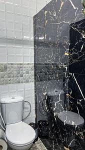 La salle de bains est pourvue de toilettes blanches et d'un mur noir. dans l'établissement Riad Dar Doura, à Rabat