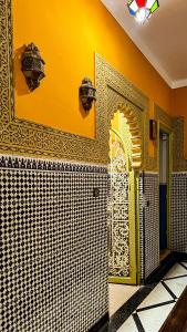 een badkamer met een gele en witte tegelmuur bij Riad Dar Doura in Rabat