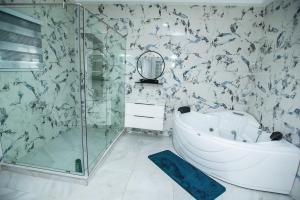 a bathroom with a tub and a glass shower at Elegant and Cosy Four Bedroom Home in Accra in Accra