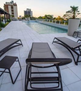 a patio with two tables and chairs next to a pool at Hermoso departamento en Skytower in Asunción