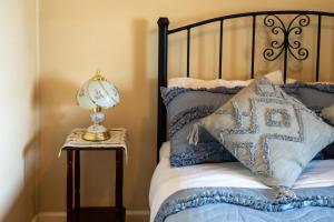 a bed with blue pillows and a lamp on a side table at Ruby's Cottage in Penola