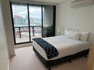 a bedroom with a bed and a large window at Winston Apartments Docklands in Melbourne