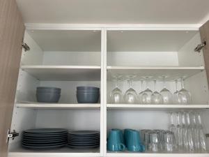 a cabinet filled with glasses and plates and bowls at Winston Apartments Docklands in Melbourne