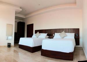 um quarto com 2 camas e lençóis brancos em Hotel Zócalo Chilpancingo em Chilpancingo de los Bravos
