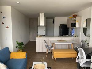 a living room with a blue couch and a kitchen at Moderno con vista, al lado de CC Mayorca y Metro in Sabaneta