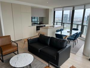 a living room with a black couch and a kitchen at Winston Apartments Docklands in Melbourne
