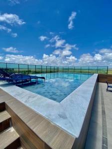 uma piscina com dois bancos no topo de um edifício em Seja um hóspede de charme num flat-boutique a 80m do mar de Porto em Porto de Galinhas