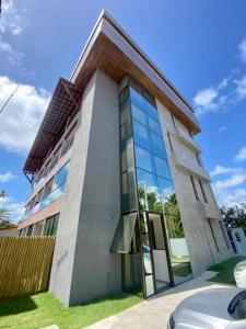 um edifício com janelas de vidro do lado em Seja um hóspede de charme num flat-boutique a 80m do mar de Porto em Porto de Galinhas