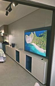 uma sala de estar com uma televisão de ecrã plano na parede em Seja um hóspede de charme num flat-boutique a 80m do mar de Porto em Porto de Galinhas