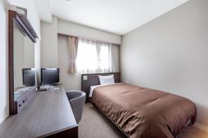 a hotel room with a bed and a desk with a television at Orange Inn Sendaihigashi in Sendai