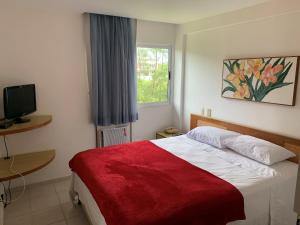 um quarto com uma cama com um cobertor vermelho e uma janela em Muro Alto Marupiara Suítes em Porto de Galinhas