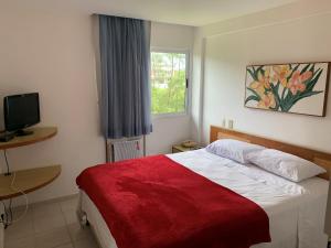 a bedroom with a bed with a red blanket and a window at Muro Alto Marupiara Suítes in Porto De Galinhas +26 photos