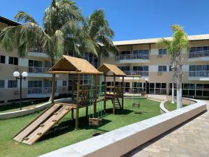 un parque infantil frente a un edificio con palmeras en Muro Alto Marupiara Suítes, en Porto de Galinhas