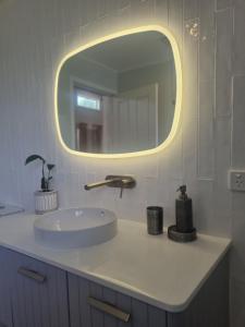 a bathroom with a sink and a round mirror at Greenhills Guesthouse in Victor Harbor