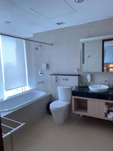 a bathroom with a tub and a toilet and a sink at The H Tower Residence by YLS Stay in Jakarta