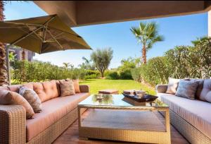 a patio with two couches and an umbrella at Appartement de luxe avec jardin privé in Marrakech